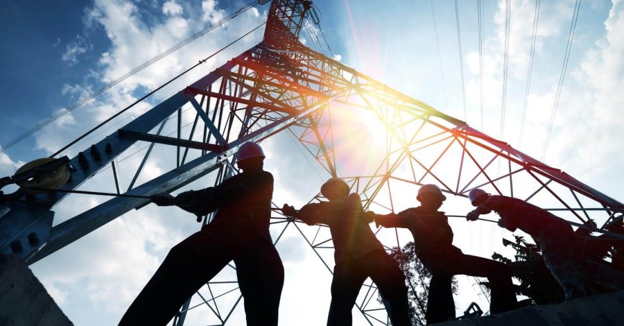 Construction workers pulling cables near a tall structure, showcasing teamwork in a construction project.