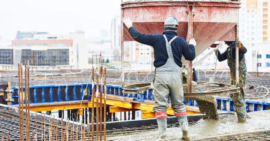 Construction workers pouring concrete from a mixer onto a building site, showcasing concrete work in progress for remodeling projects.